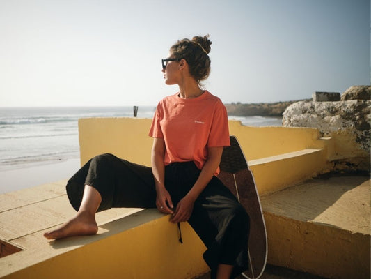 Femme portant un t-shirt NIKN avec dreamer Embroidery assise tranquillement au bord de la mer et regardant l'immensité.