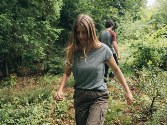 Sur le chemin dans la forêt, une femme et un homme en NIKIN TreeShirt Café Carbone.