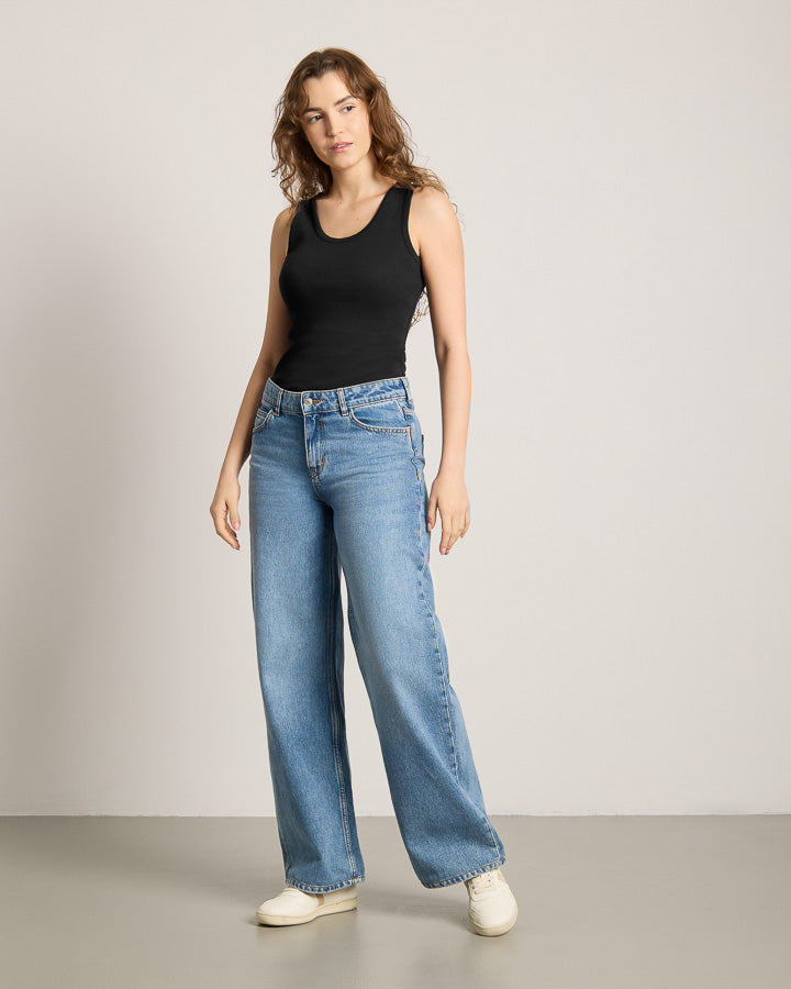 NIKIN  women Black Top, loose fit, paired with blue wide-leg jeans and white shoes.